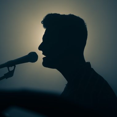 a silhouette of a man singing into a microphone