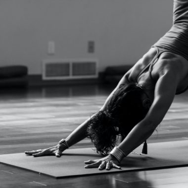 woman in black tank top and black pants bending her body on floor