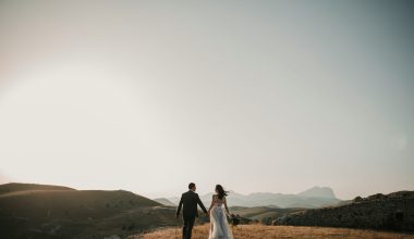 a bride and groom walking on a hill