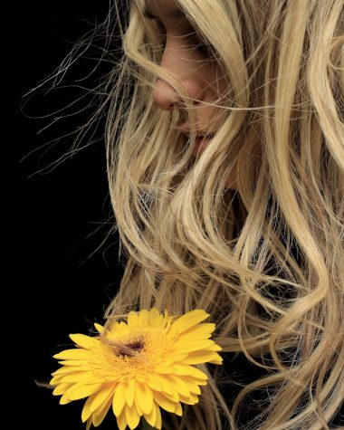 woman with blonde hair holding yellow flower