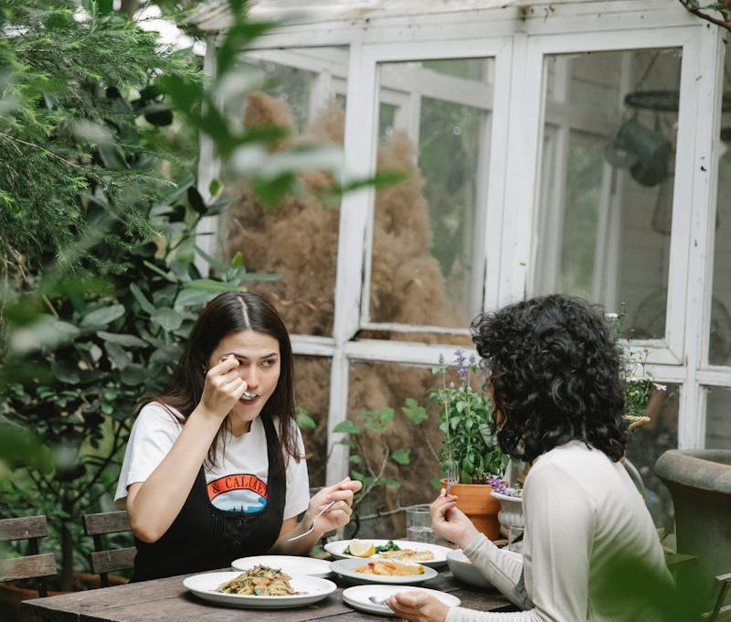Female gardeners eating lunch at table in backyard