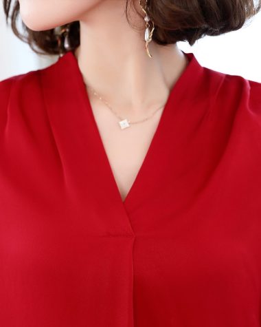 A woman in a red blouse with a necklace.