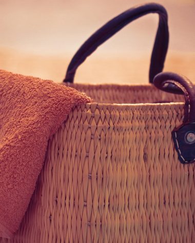 Gevlochten strandtas op een zandstrand in de zomer