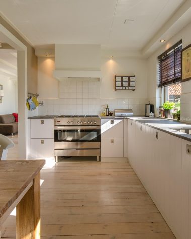 Open keuken die naadloos overgaat in de woonkamer, met geïntegreerde apparaten en een strakke uitstraling