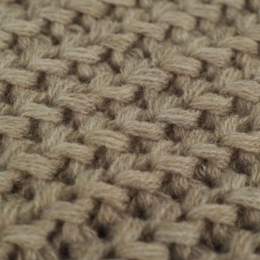 Close-up van een handgebreide wollen trui in natuurlijke kleur met zichtbare textuur