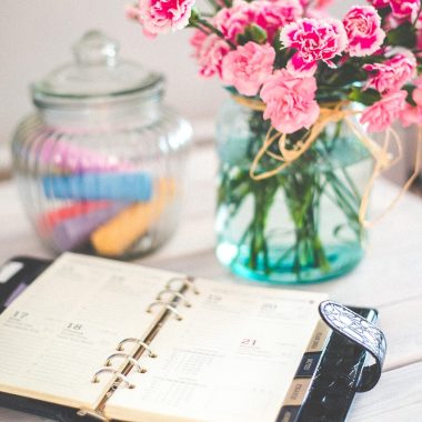 Een opengeslagen weekplanner op een bureau met een pen ernaast, klaar om een huishoudschema in te vullen
